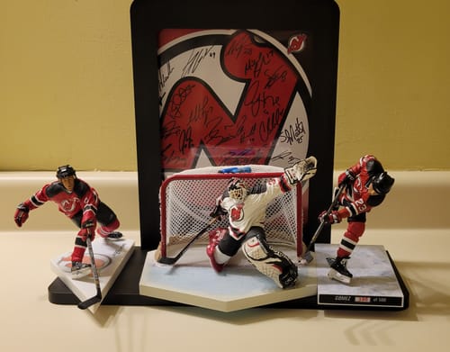 Nerd Hero shelf holding signed New Jersey Devils art with hockey figurines on the ledge
